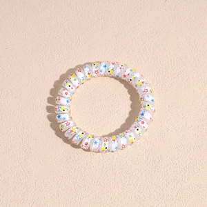 Detail of spiral hair tie featuring colorful star patterns on white plastic material