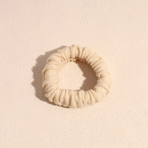 Dettaglio della trama in tessuto crema spesso e del design a coste dell'elastico per capelli