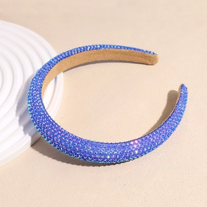 Gros plan du serre-tête large serti de strass bleus étincelants sur un tissu beige