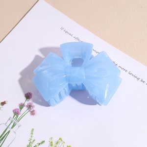 Detailed view of light blue jelly acrylic bow hair claw clip with smooth polished finish
