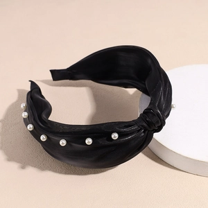 Détail d'un serre-tête en satin noir avec nœud élégant et perles incrustées