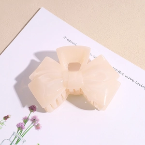 Detail of elegant cream apricot acrylic bow hair claw clip showing smooth resin texture