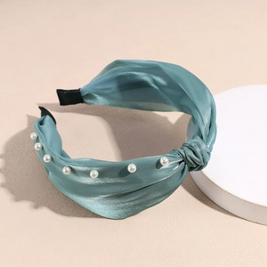 Détail d'un serre-tête en satin sarcelle avec perles et nœud élégant
