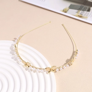 Detail of gold pearl headband with butterfly accents on a white decorative pedestal