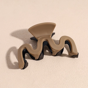 Détail de la pince à cheveux mate ondulée au design bicolore kaki et marron foncé élégant