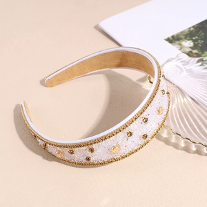 Sparkling wide headband with amber rhinestones and gold trim on beige background