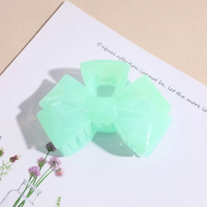 Detailed view of a light green jelly acrylic bow hair claw clip with a glossy finish