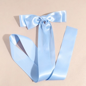 Detailed view of light blue satin bow hair clip with long silk ribbons and glossy finish