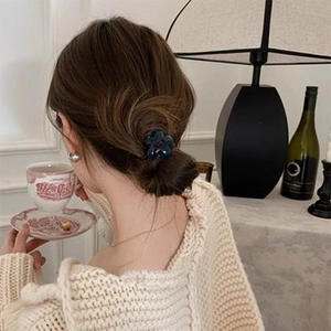 Élastique à cheveux fleur en acrylique bleu marine porté dans un cadre lifestyle élégant