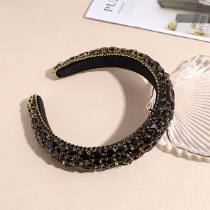 Luxurious black rhinestone padded headband with gold metal base on an elegant background