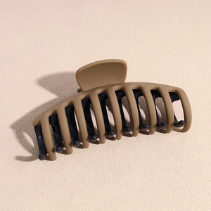 Gros plan d'une grande pince à cheveux mate avec un design bicolore café et bleu marine
