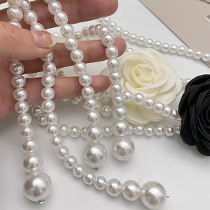 Detailed close-up of multi-layer camellia pearl belt and necklace with large beads
