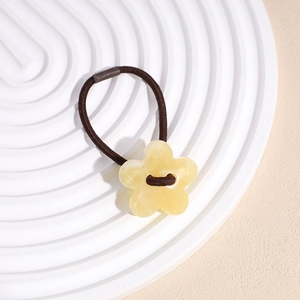 Détail d'un élastique à cheveux marron foncé avec pendentif fleur en acrylique jaune