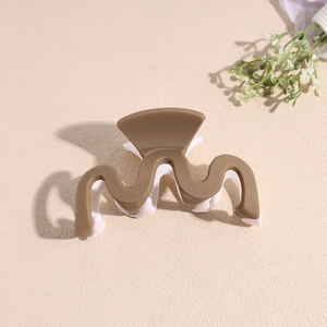 Détail d'une pince à cheveux bicolore ondulée en résine mate marron et blanc crème