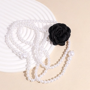 Detail of layered pearl belt with a black camellia flower for elegant dress styling