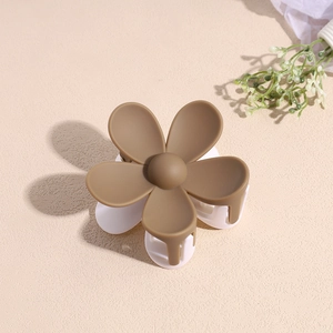 Détail de la pince à cheveux fleur mate marron moka et blanc crème sur fond beige