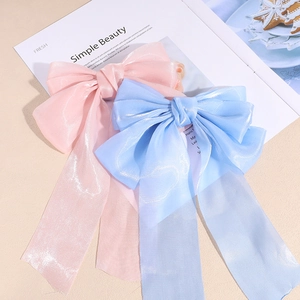 Barrettes à nœuds rose et bleu avec de longs rubans sur un fond beige minimaliste