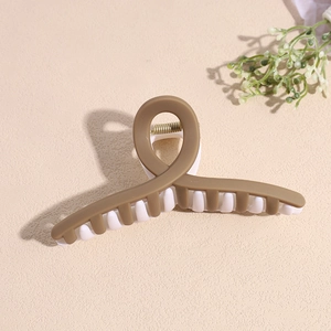 Gros plan sur une pince à cheveux mate café et blanc avec un design croisé géométrique