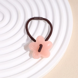 Détail d'un élastique fleur en acrylique rose avec cordon marron sur présentoir blanc