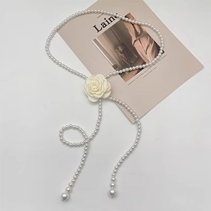 Detailed view of elegant white camellia flower on a long pearl chain belt and necklace