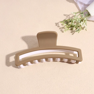 Détail de la grande pince à cheveux mate bicolore avec un design creux rectangulaire marron