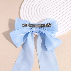 Barrette à cheveux avec grand nœud bleu clair et longs rubans sur support minimaliste
