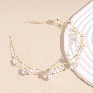 Detail of elegant double-layered golden headband with white faux pearls on stone prop