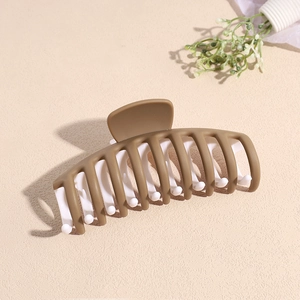 Détail de la pince à cheveux mate avec design bicolore marron et blanc et dents multiples