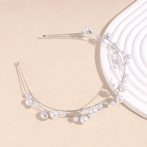 Close-up of elegant double-layered silver hairband with scattered pearls and rhinestones