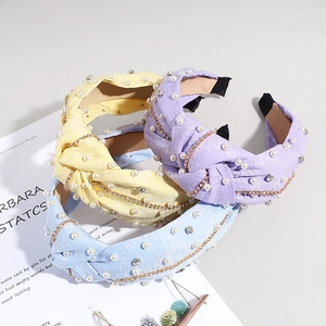 Détail de serre-têtes torsadés avec perles blanches et petits strass aux tons macaron