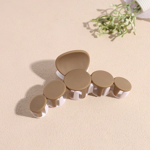Détail d'une pince à cheveux mate bicolore marron et blanche au design géométrique circulaire