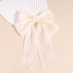Vue détaillée de la pince à cheveux avec nœud en organza crème et longs rubans fluides