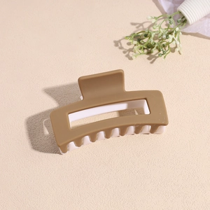 Détail d'une pince à cheveux rectangulaire mate bicolore marron et blanc avec découpe
