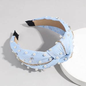 Détail d'un serre-tête noué bleu clair avec des perles blanches et des chaînes de strass