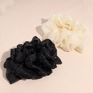 Détail de grandes pinces à cheveux à nœuds en mesh noir et beige avec paillettes subtiles