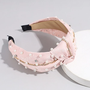 Détail d'un serre-tête rose noué avec perles et décoration de chaîne de strass étincelants