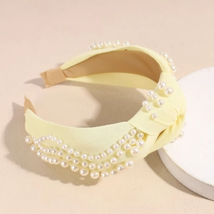 Détail du serre-tête noué jaune en tissu texturé orné de perles élégantes et raffinées