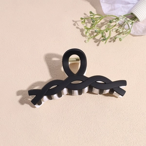 Détail de la pince à cheveux bicolore noir et blanc mat avec ressort en métal doré