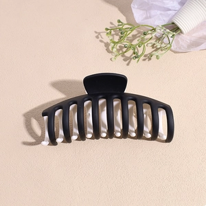 Détail d'une grande pince à cheveux mate noire et blanche avec dents denses et arrondies