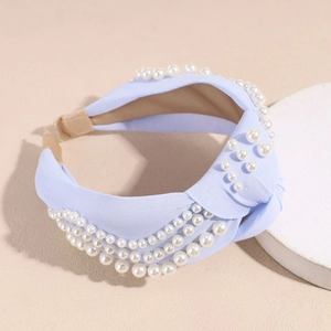 Détail d'un serre-tête noué bleu clair avec plusieurs rangées de perles blanches et tissu