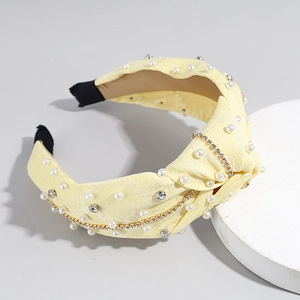 Détail du serre-tête noué jaune orné de perles blanches et de chaînes de strass