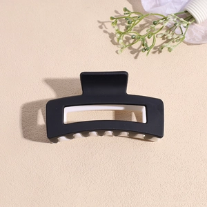 Détail d'une pince à cheveux carrée mate avec un design contrasté noir et blanc