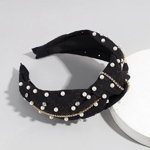 Détail du serre-tête à nœud noir orné de perles blanches et de strass brillants