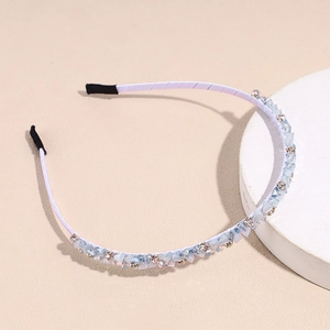 Macro view of light blue crystals and rhinestones on a white fabric-wrapped headband