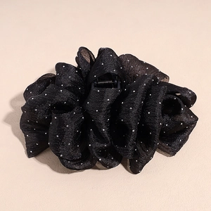 Détail de la pince à cheveux noire en tissu superposé avec des paillettes argentées