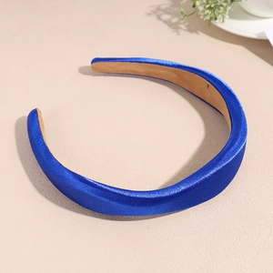 Détail du serre-tête en satin bleu roi avec rembourrage en éponge sur fond de texture beige