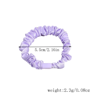 Detailed macro view of purple pleated satin hair tie with sizing at 5.5cm diameter