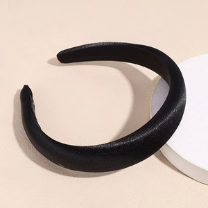 Detail of a wide black satin headband with thick padding on a white stone display
