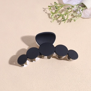 Détail de la pince à cheveux géométrique mate noire et blanche avec motifs circulaires