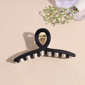 Vue détaillée de dessus d'une pince à cheveux géométrique noir et blanc mat à ressort doré
